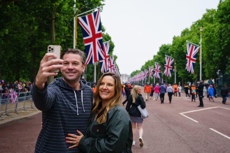 People pose for selfies on the Mall ahead of the start of the Platinum Jubilee Pageant in front of Buckingham Palace. PA