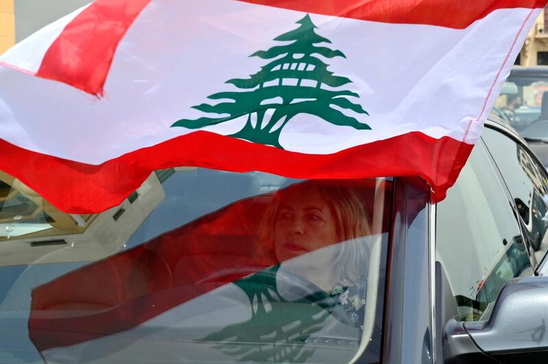 An anti-government protester puts a Lebanese flag on her car during a parade to protest the economic situation in downtown Beirut, Lebanon, EPA