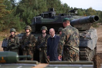 German Chancellor Olaf Scholz talking with soldiers in front of a Leopard 2 battle tank. AFP