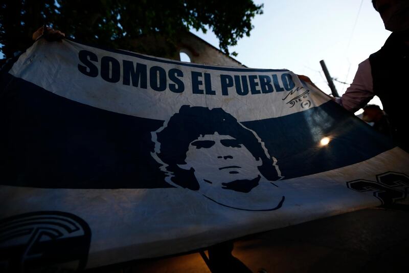Fans show a flag with the face of Diego Maradona at Clínica Olivos. Getty Images