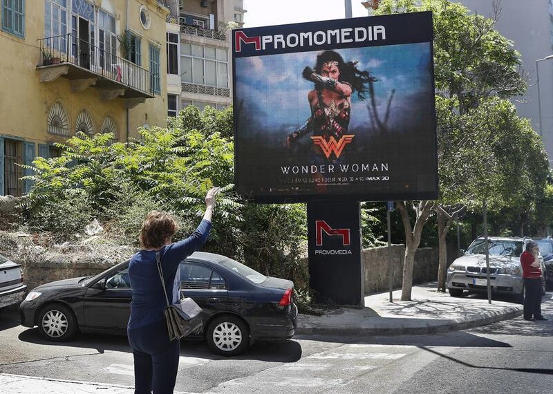 A woman waves for a taxi in front of a digital billboard promoting the 2017 Wonder Woman movie in Beirut on May 30, 2017. Hussein Malla / AP Photo