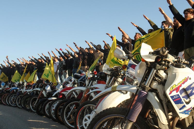 TOPSHOT - Supporters of the Lebanese Shiite movement Hezbollah perform a salute as they stand behind motorcycles carrying the group's flags in the southern Lebanese district of Marjayoun on the border with Israel on May 25, 2020. Twenty years after the withdrawal of Israeli forces from Lebanon, Hezbollah still enjoys wide support among youth regaled with tales of the Shiite group ending 22 years of Israeli occupation. / AFP / Mahmoud ZAYYAT
