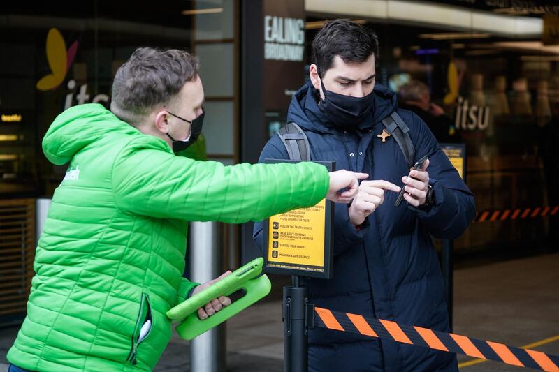 A worker helps a customer find a barcode on his phone as he prepares to enter the store. AFP