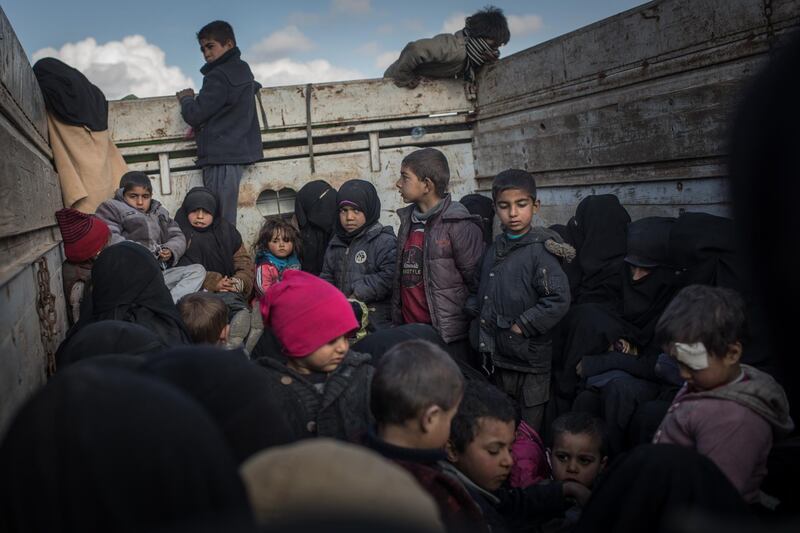 Women and children who have fled fighting in Bagouz look out the back of a truck. Getty Images