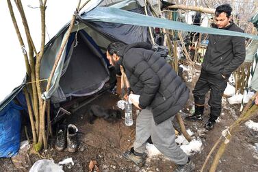 Migrants from Asia stand near a makeshift tent as they seek shelter from sub-zero temperatures in an improvised tent-jungle camp located in the woods near the north-western Bosnian town of Bihac. AFP