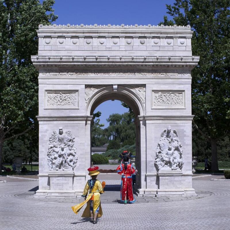 Two Chinese wearing traditional royal family costumes walking towards a mini replica of the Arc de Triomphe in Beijing World Park, in suburb Beijing. Beijing World Park, with a collection of mini replicas of famous architectures from all over the world, attempts to give visitors a chance to see the world without having to leave the capital.