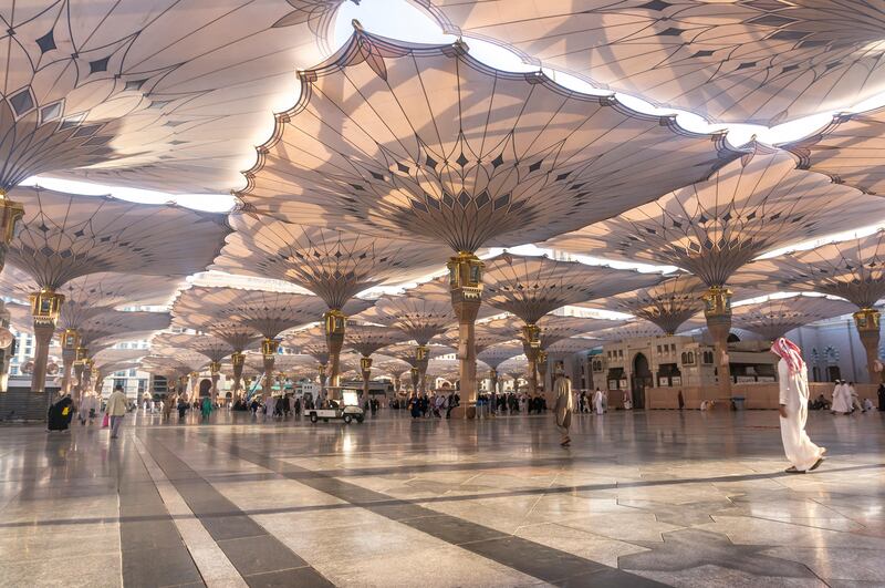 EWXH6E MEDINA, SAUDI ARABIA - MARCH 06, 2015 : Pilgrims walk underneath giant umbrellas at Nabawi Mosque compound. Mawardi Bahar / Alamy Stock Photo