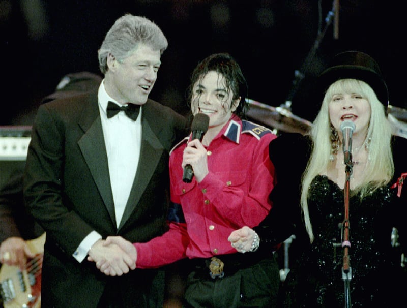 President-elect Bill Clinton (L) shakes hands with singer Michael Jackson as Stevie Nicks of the Fleetwood Mac band sings at the finale of a star-studded gala on the eve of the inauguration at the Capital Center January 19