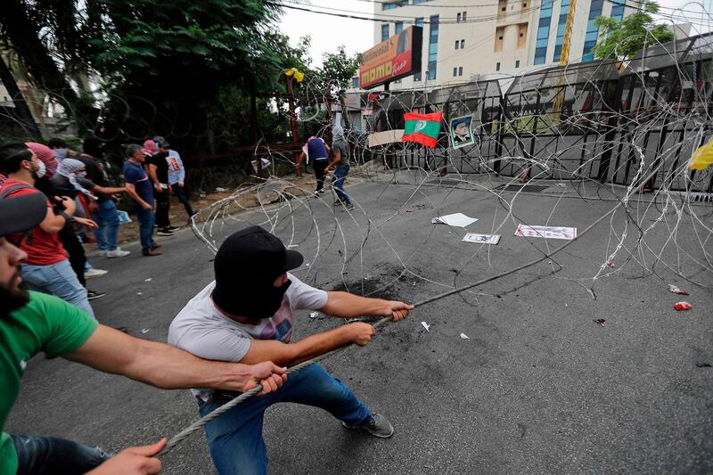 Protesters pull barbed-wire closing off a street during an anti-US demonstration near the United States' Embassy headquarters in Awkar, Lebanon. AFP
