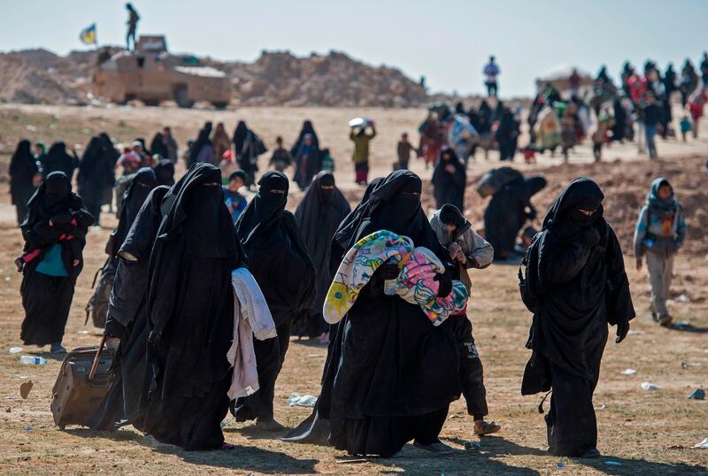 TOPSHOT - Fully veiled women and children fleeing from the Baghouz area in the eastern Syrian province of Deir Ezzor walk in a field on February 12, 2019 during an operation by the US-backed Syrian Democratic Forces (SDF) to expel hundreds of Islamic State group (IS) jihadists from the region. The ferocious battle for the Islamic State group's last bastion in eastern Syria entered its fifth day, as exhausted families left the ever-shrinking scrap of land where holdout jihadists have been boxed in by Kurdish-led forces. / AFP / Fadel SENNA
