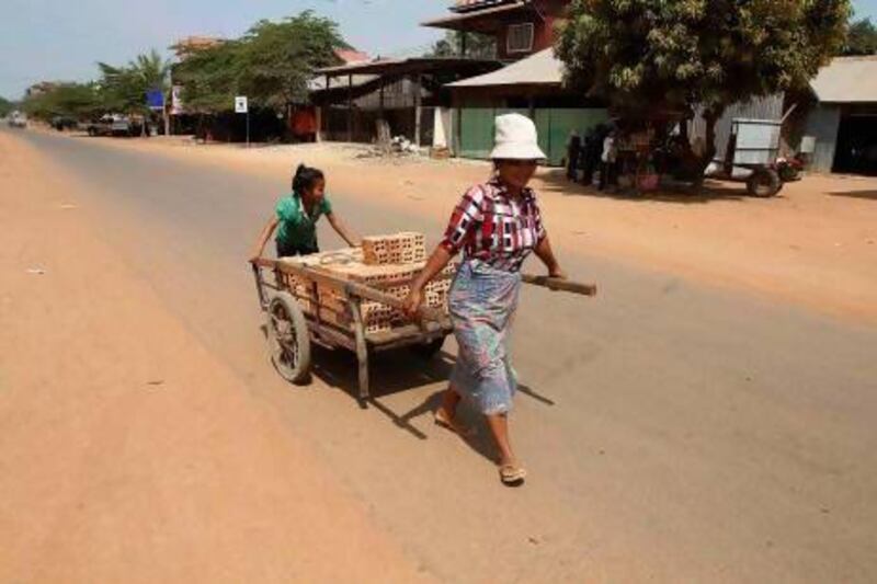 A woman and her daughter transport a cart of bricks in Rovieng. The remote district of Rovieng was once a battleground between Cambodian government troops and Pol Pot's genocidal Khmer Rouge. Samarang Pring / Reuters
