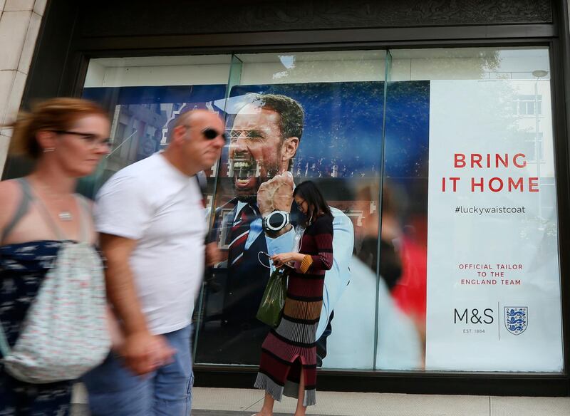 Shoppers pass the window of a Marks and Spencer store displays an image of England head coach Gareth Southgate in London, showing support for the England soccer team. The soft-spoken Southgate in a simple blue waistcoat seems to be uniting Britain amid dreams of victory in soccer's World Cup, with their next match against Croatia on upcoming Wednesday. (Robert Stevens/AP Photo)