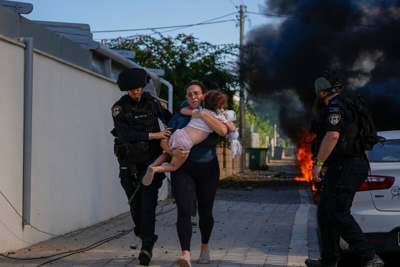 Israeli police officers evacuate a woman and a child from a site hit by a rocket fired from the Gaza Strip. AP 