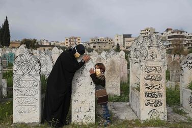 A displaced Syrian woman and her daughter visits a grave of a relative in the town of Ariha in the northern countryside of Syria's Idlib province on April 5, 2020. AFP
