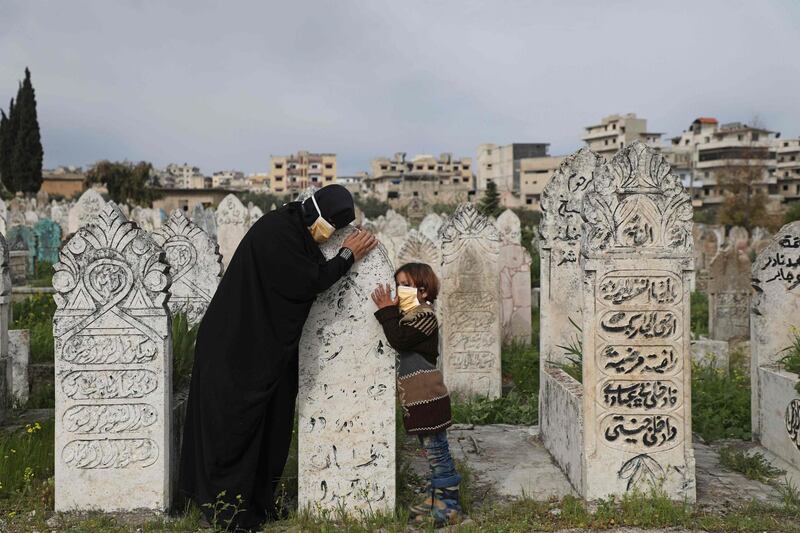 TOPSHOT - A displaced Syrian woman and her daughter visits a grave of a relative in the town of Ariha in the northern countryside of Syria's Idlib province on April 5, 2020.  / AFP / AAREF WATAD
