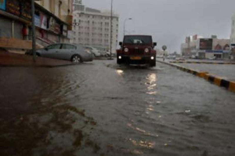 A car drives in a deserted and dark flooded street in Muscat on June 4.