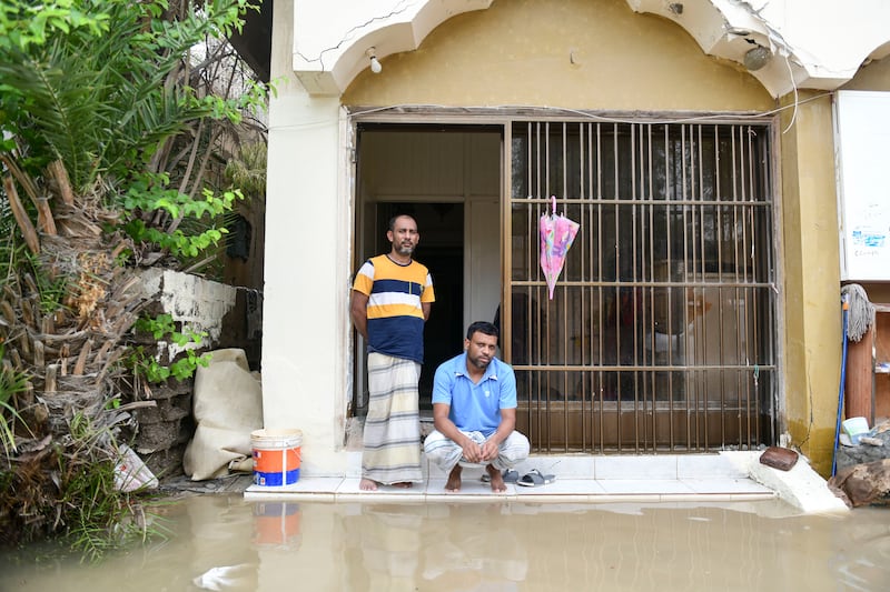 Residents Tarikul Alauddin and Mojammel Ali, from Bangladesh, outside their house in Kalba, which was heavily damaged by flooding and left with no electricity. Khushnum Bhandari / The National