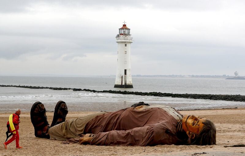 A lifeguard passes one of Royal Deluxe's giant marionette puppets on the beach at New Brighton, north-west England. Reuters