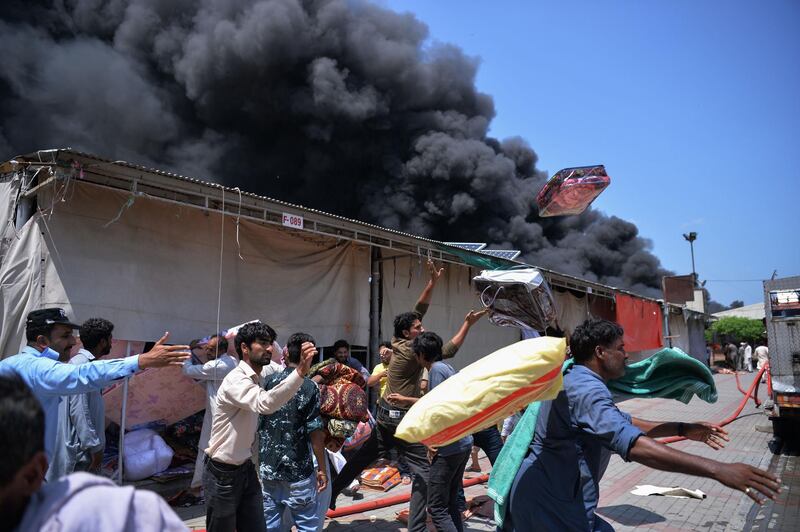 Pakistani traders throw goods from shops to save them from perishing in the fire.