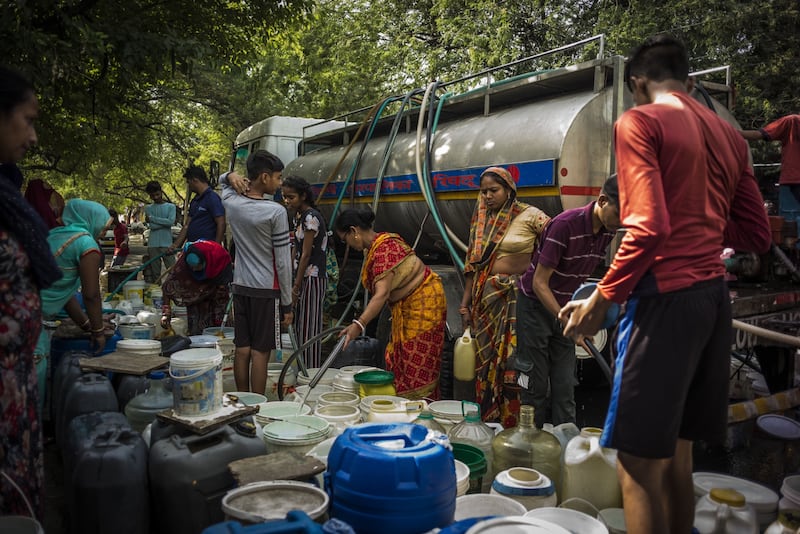 Residents of New Delhi fill containers with water from a municipal tanker. Bloomberg