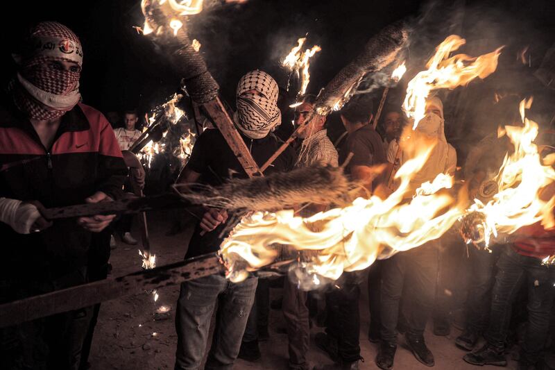 Palestinian protesters gather with torches during a demonstration against the outpost.