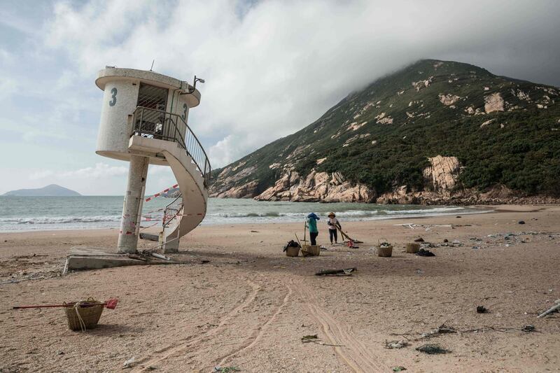 Workers clear debris on a beach in Hong Kong after Typhoon Mangkhut. Dale De La Rey / AFP