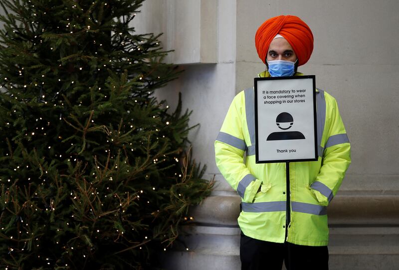 A security guard stands by a sign asking customers to wear face masks at a store in London. Reuters