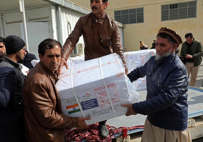 Afghan health ministry workers unloads boxes of the first shipment of 500,000 doses of the AstraZeneca coronavirus vaccine made by Serum Institute of India, donated by the Indian government to Afghanistan, at the customs area of the Hamid Karzai International Airport, in Kabul, Afghanistan, Sunday, Feb. 7, 2021. (AP Photo/Rahmat Gul)