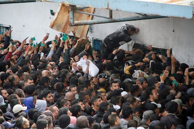 Palestinians gather to receive aid outside a UN warehouse, in Gaza City, on March 18, 2024. Reuters