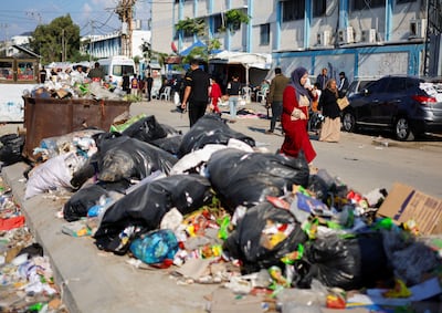 Palestinians walk past piles of rubbish that threaten to spark an environmental catastrophe, Reuters