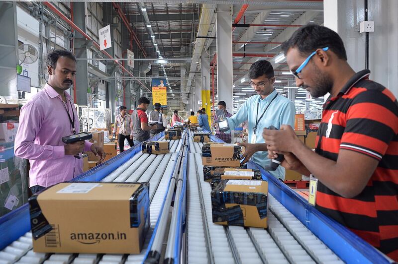 Employees of Amazon India scan packages at Amazon's newly launched fulfilment centre on the outskirts of Bangalore on September 18, 2018. - The US-headquartered online retail giant Amazon opened its latest fulfilment centre in Karnataka as part of its long-term, multi-billion-dollar bid to expand its footprint in India's growing e-commerce industry. (Photo by MANJUNATH KIRAN / AFP)