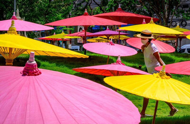 A woman walks through the middle of a decorative installation of colourful paper umbrellas in Bangkok, Thailand. AFP