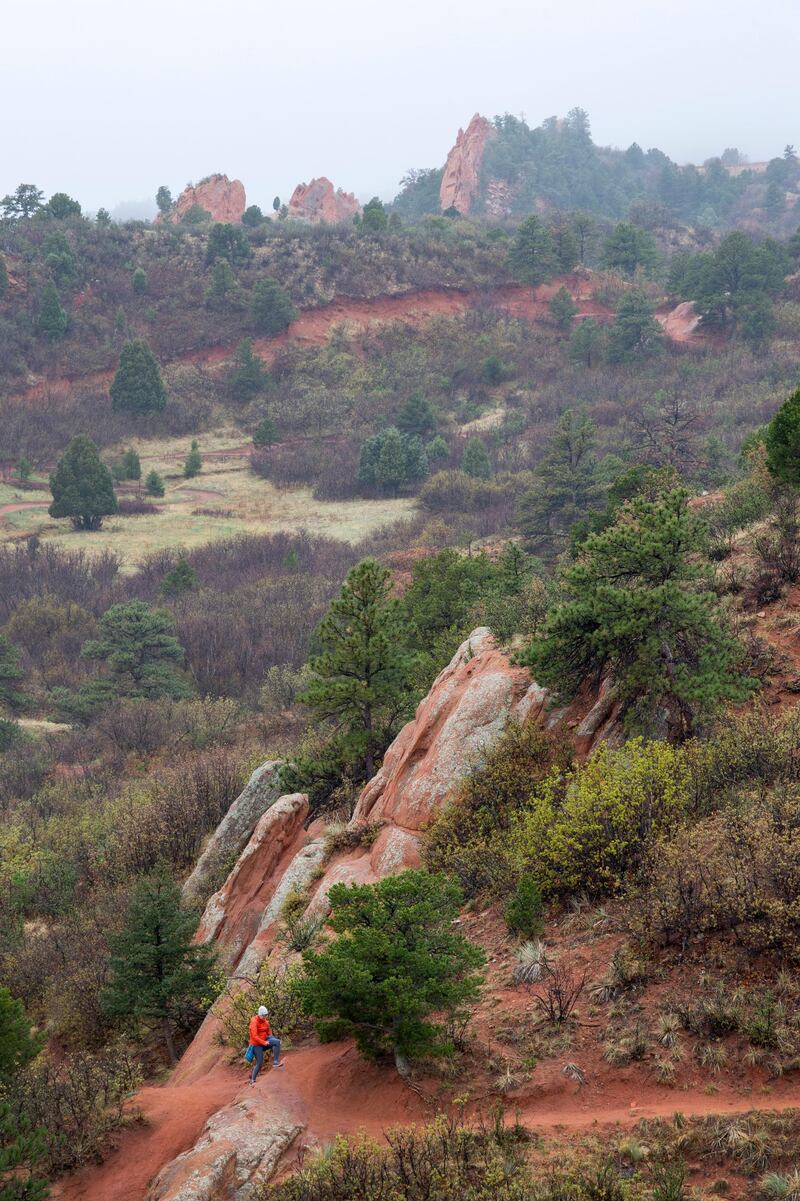 A visitor hikes the quiet Quarry Pass Trail in Red Rocks Canyon Open Space, Monday, May 10, 2021, as a drizzle soaks the Colorado Springs, Colo., park. Rain and snow is expected in the Pikes Peak Region until Wednesday. (Christian Murdock/The Gazette via AP)