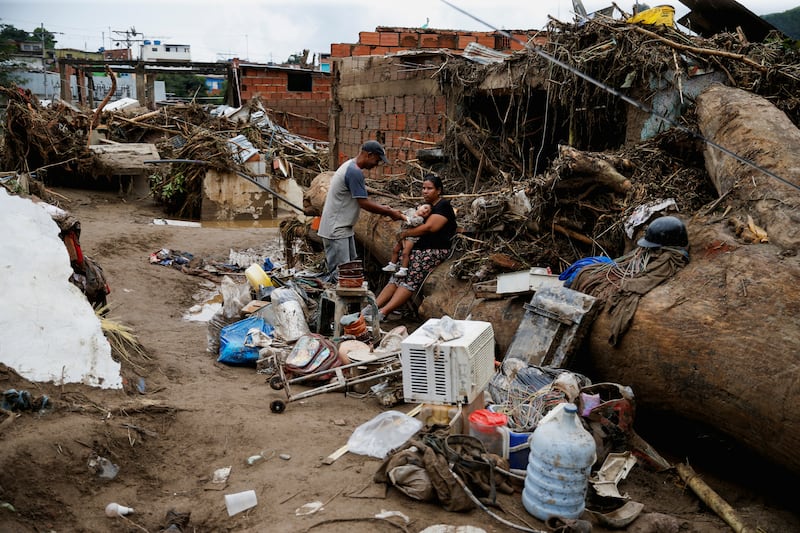 People sit surrounded by belongings following the floods, in Tejerias. Reuters