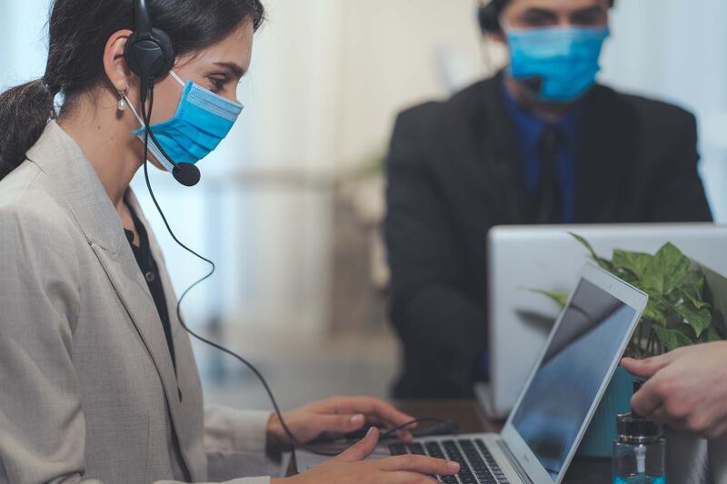 Service desk consultant talking on hands-free phone. Call center. Getty Images