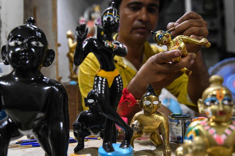 An artist applies finishing touches to an idol of Krishna at a workshop in Amritsar. AFP