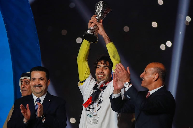 Iraq's national football team captain Jalal Hassan (C) lifts the Gulf Cup trophy as Prime Minister Mohammed Shia Al Sudani (L) and football federation president Adnan Derjal (R) applaud.  AFP