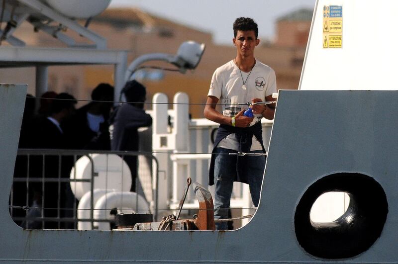 A migrant looks on from Italy's Diciotti coast guard vessel carrying 67 asylum seekers berthed at Trapani port on July 12, 2018.  The migrants were rescued off Libya on July 10 by a private Italian vessel oil-rig tug Vos Thalassa and then transferred to the coast guard ship in a case that has caused tension within the government. ItalyÕs Interior Minister and deputy PM Matteo Salvini says today from migrants summit in Innsbruck "I do not authorize anyone to get off" / AFP / Alessandro FUCARINI
