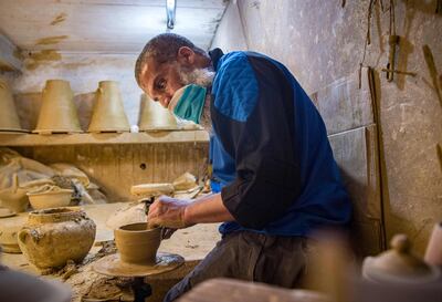 A Moroccan potter works on a wheel at a workshop in the city of Sale, north of the capital Rabat, on June 3, 2020, during the novel coronavirus pandemic.  Artisans in Morocco have been starved of income for almost three months because of the COVID-19 pandemic. The crafts industry represents some seven percent of GDP, with an export turnover last year of nearly 1 billion dirhams ($100 million). / AFP / FADEL SENNA
