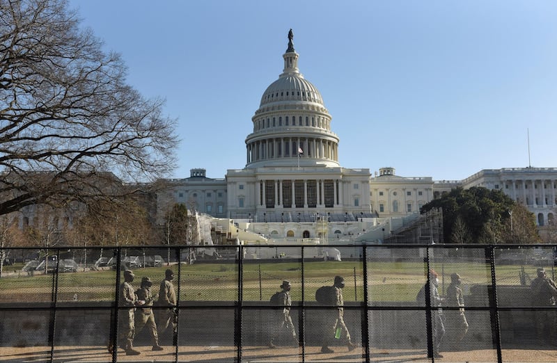 National Guard members walk behind a fence installed in front of the US Capitol, a day after supporters of Donald Trump stormed the building. Reuters