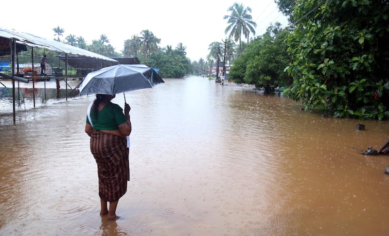 A woman stands on a flooded street in Kochi. EPA