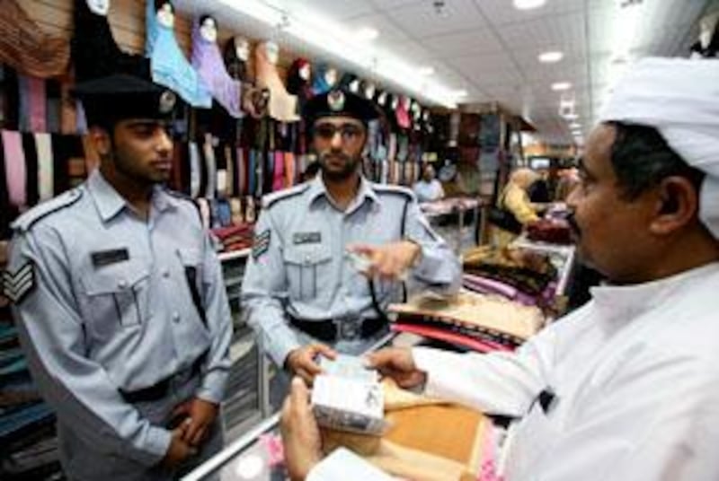 Abu Dhabi - April 6th ,  2008 - L to R ,Basem Hassan Al Naimi and  Khalid Ismaeel Al Bloushi   Community Police officers  in Abu Dhabi speak to shop keepers  on patrol at the Madinet Zayed Shopping Centre,Central Abu Dhabi to go with words by Mahmoud Habboush  ( Andrew Parsons  /  The National )