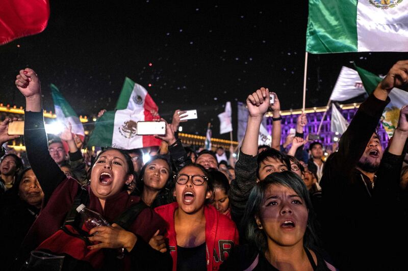 TOPSHOT - Supporters of the presidential candidate for the "Juntos haremos historia" coalition, Andres Manuel Lopez Obrador, celebrate at the Zocalo square in Mexico City, after getting the preliminary results of the general elections on July 1, 2018.  Anti-establishment leftist Andres Manuel Lopez Obrador won Mexico's presidential election Sunday by a large margin, according to exit polls, in a landmark break with the parties that have governed for nearly a century. / AFP / Guillermo Arias
