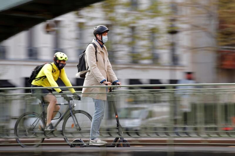 A man rides a scooter past a biker on a bridge over the canal Saint-Martin in Paris, France. Reuters