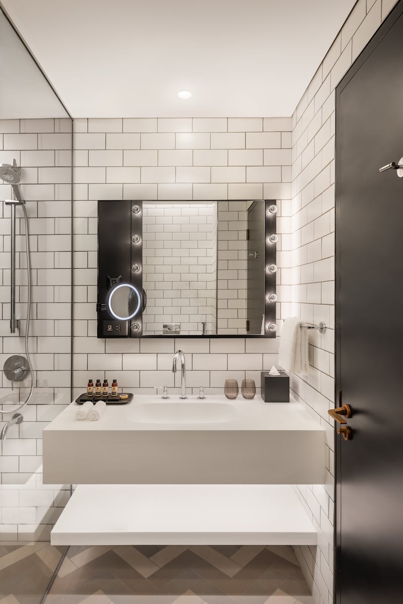 White subway tiles and Hollywood-style lights in a guest bathroom. Photo: Hilton 