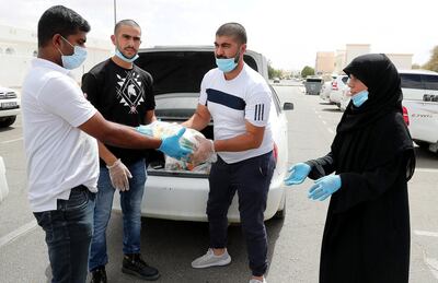 AL AIN, UNITED ARAB EMIRATES , May 03 – 2020 :- Right to Left- Areej Jihad , Ahmad Issam and Mohammed Issam  distributing the raw food packets to the needy in Al Ain.  Areej Jihad is 40 years old and misses Iftar at home every day to help deliver food to the needy in Al Ain. (Pawan Singh / The National) For News. Story by Salam