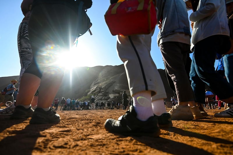 Tourists line up waiting to climb Uluru. AAP Image via AP