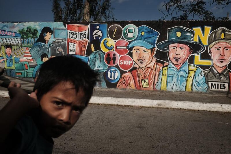 A boy walks past a colourful mural of dads and men in various jobs, in a street in Mabalacat, Pampanga.