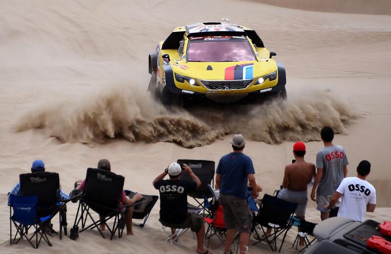 Peugeot's British driver Harry Hunt and Dutch co-driver Wouter Rosegarr are watched by rally fans. AFP