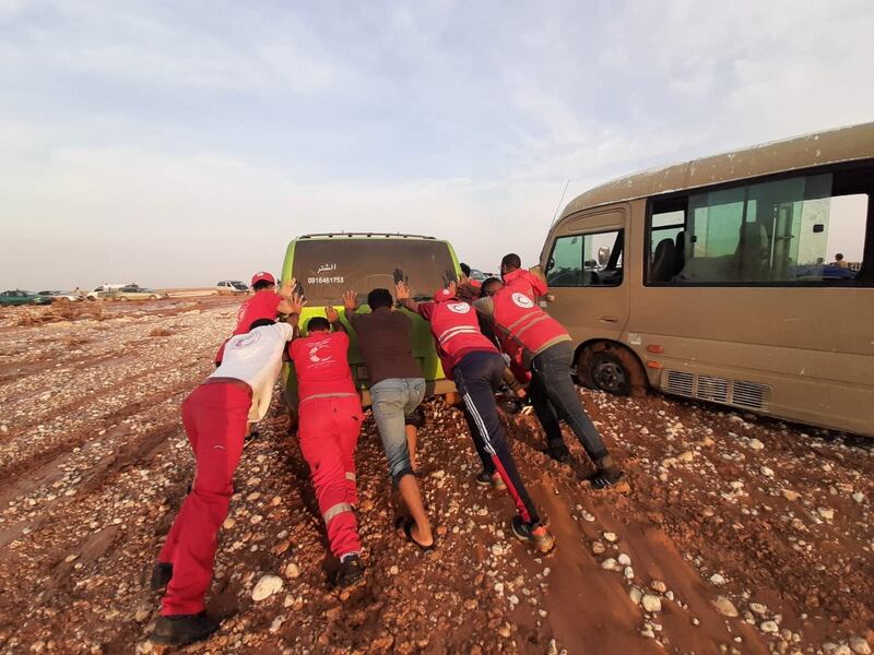 Members of Libyan Red Crescent Ajdabiya push a vehicle through the mud in an area affected by flooding. Reuters